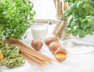 spaghetti and eggs on background of glass of milk and green herbs
