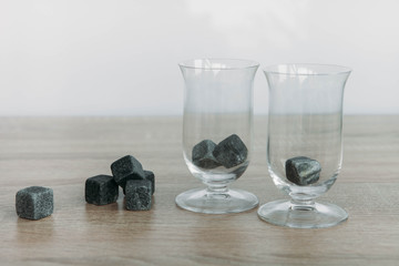 Stones for cooling whiskey and glases tulup on light wooden background
