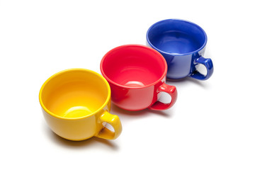 yellow ,red and blue cup in parallel over isolated white.high angle view