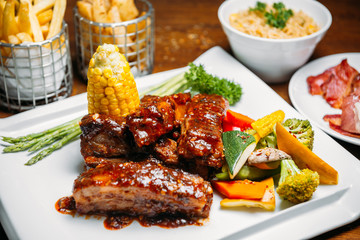 Pork ribs steak with vegetables, corn, rice and fries garnish