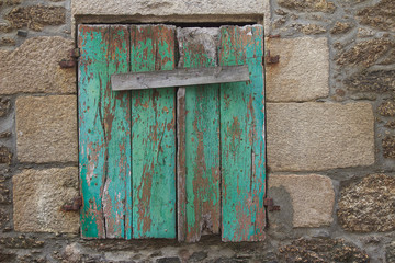 Vintage turquoise shutter on stone wall