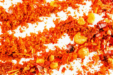 Dry crushed chili flakes and powder isolated on white. Food background. Closeup macro shot. Top view.