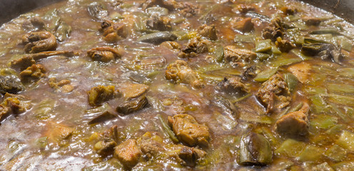 Cooking authentic Valencian paella with chicken meat, rabbit meat, vegetables, boiling Valencian rice, saffron. Typical cuisine of the Valencia Spain. Boiled bubbles in motion