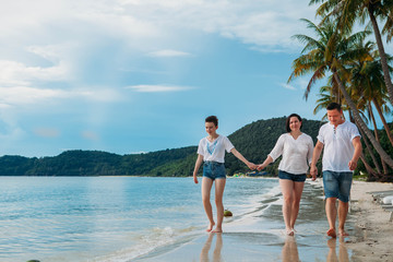 Happy family walking along tropical beach