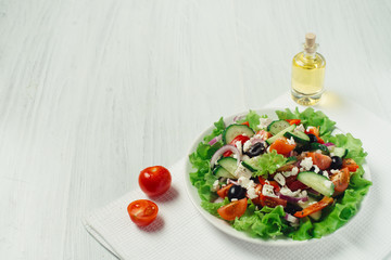 Greek salad with olive oil and tomatoes on a white table side