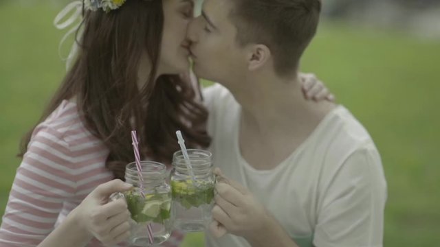 Verliebtes Paar k&uuml;sst sich mit Limonade beim Picknick im Garten