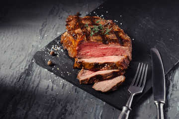 Sliced Steak of pork with rosemary on slate Board