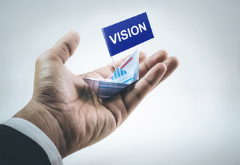 Vision word on flag with boat made of paper graph in businessman hand.business financial concept.