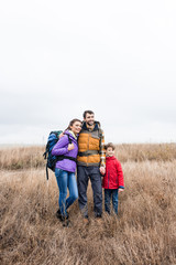 Happy family with backpacks standing in grass