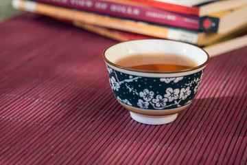 Closeup of a cup of tea and books in an outdoor shaded light ambiance