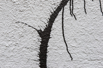 Dripping black spray paint splatter on white wall texture background