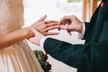 Loving couple holding hands with rings against wedding dress