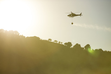 GRANADA, AUGUST 28: Fire fighting Helicopter, with bambi basket, during a fire fighting in the bush. August 28, 2014, Granada, Spain.
