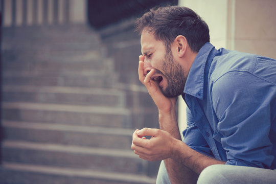 sorrowful crying man sitting on steps outdoors