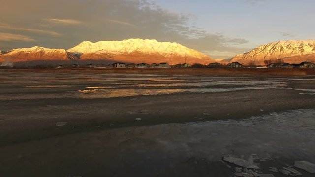 Flying backwards over icy landscape viewing snow capped mountains