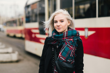 Street stylish portrait of a young and beautiful woman on the background of the urban landscape. Girl on a background of public transport