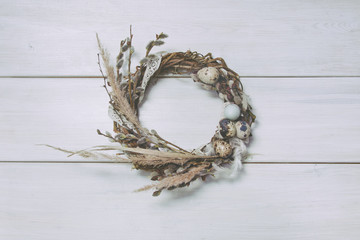 Wreath with willow and eggs on wooden background