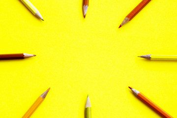 Colored crayons on a yellow background, arranged in a circle