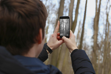 Man takes pictures of the park on a smartphone