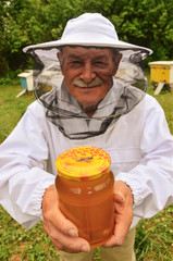 pszczelarz w pasiece prezentujący słoik miodu
 - obrazy, fototapety, plakaty