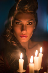 Beautiful woman in the dark room with a lot of candles