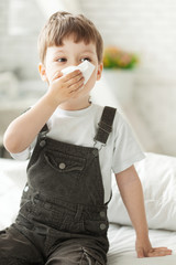 boy wipes his nose with a tissue