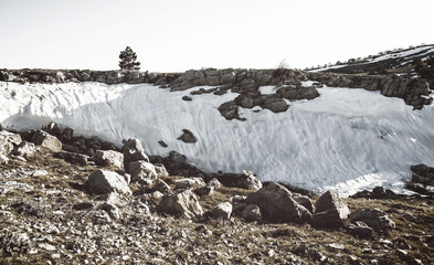Landscape on the mountain stones, snow, under the bright sun, in retro style