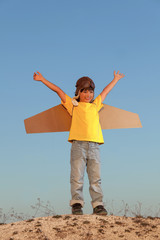 Happy boy with cardboard boxes of wings against sky dream of flying