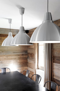 interior decoration of an old renovated wooden chalet with industrial-style dining room, black table, metal lamps and chairs and wooden wall