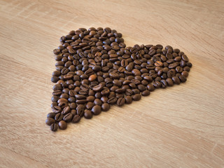 Heart shape of roasted coffee beans over wooden table