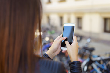 frau ist in der stadt unterwegs und schaut auf ihr mobiltelefon
