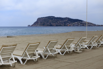 Backview of white sunbeds at sandy beach