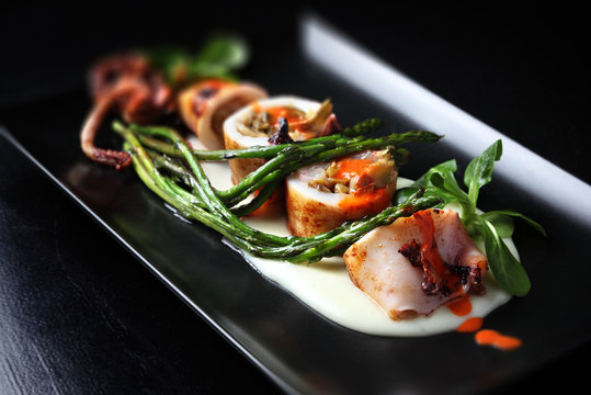 Roasted squid with shrimps and asparagus, resting on potato sauce.