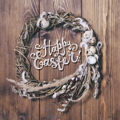 Wreath with willow and eggs on a wooden background