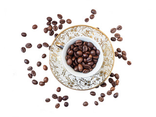 Scattered coffee grains with oriental cup filled with beans over white background from top view