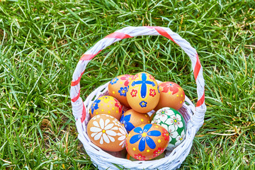 Wicker basket with hand-painted easter eggs on green grass
