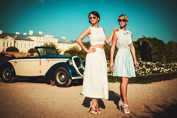 Two stylish ladies near classic convertible