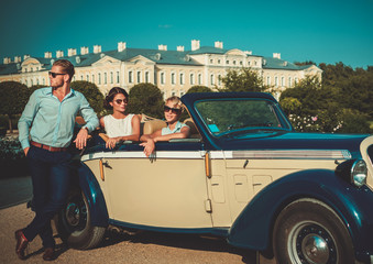 Wealthy friends near classic convertible