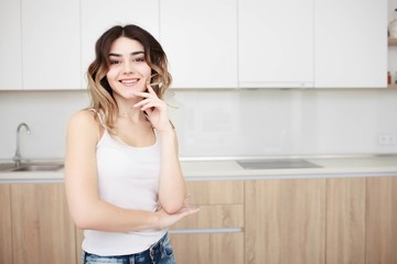 Pretty young woman standing in kitchen and smiling.