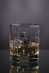 glass of whisky with ice on a grey background