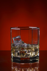 glass of whisky with ice on a red background