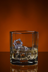 glass of whisky with ice on a orange background