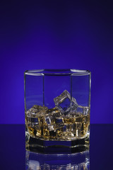 glass of whisky with ice on a blue background