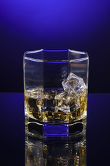 glass of whisky with ice on a blue background