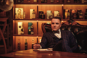 Confident upper class man with glass of beverage in gentlemen's club