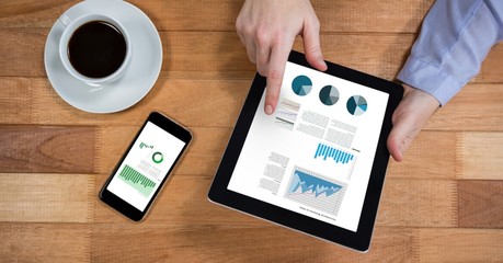 Businessman analyzing graphs on digital tablet at wooden desk