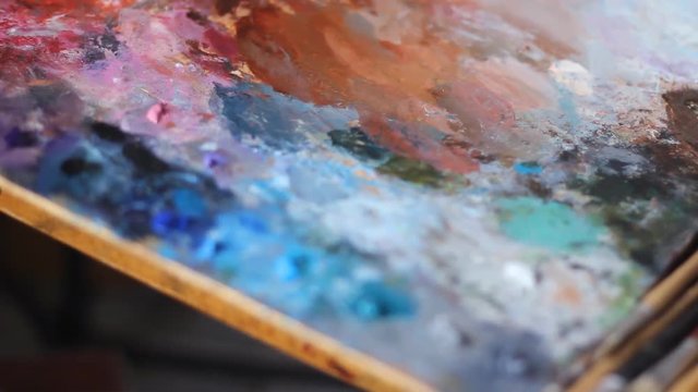 A rainbow of five neon colors dance together and mix on top of a speaker in slow motion shot on phantom flex a colorful palette of oil paint on a plywood Board.