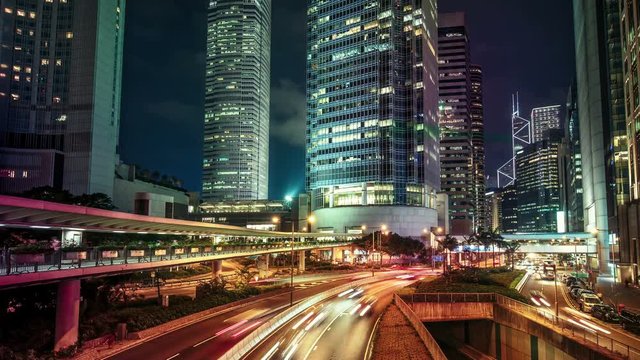 Roads with car trails in Hong Kong financial district at night. Scenic view of big illuminated city with skyscrapers and fast moving traffic. Colourful 4K Time lapse. 