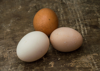 Three fresh chicken eggs on an old wooden background