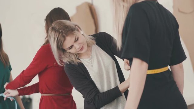 Close-up: The seamstress measures the waist size using a centimeter tape. Female fashion designer taking measurement with model. Close-up.Young needlewoman taking measures of female client.